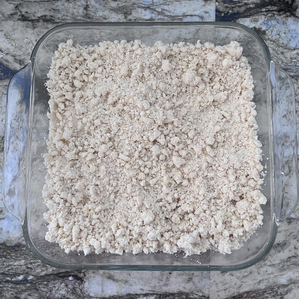 Shortbread biscuit recipe dough, poured into a glass baking dish, before pressing it down.