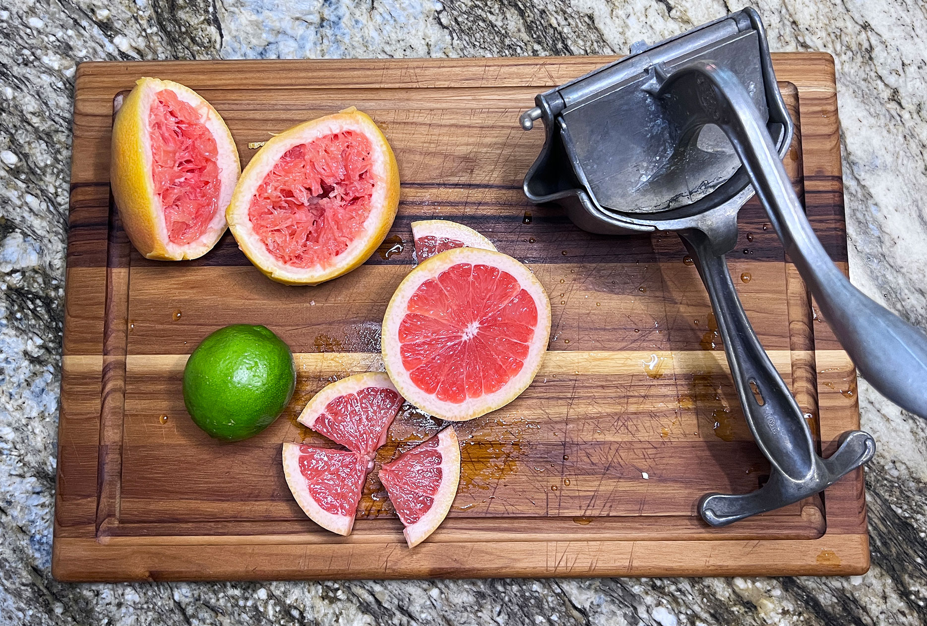 making fresh juice for spicy grapefruit margarita, vintage juicer, grapefruits and lime shown on a wood cutting board